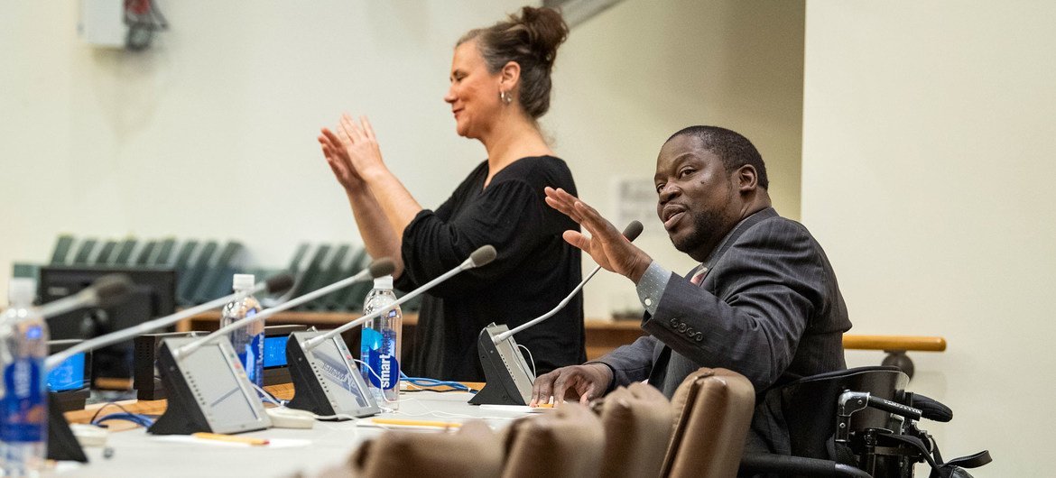 A sign language interpreter translates for actor Daryl Mitchell (seated) during a special event at the UN.