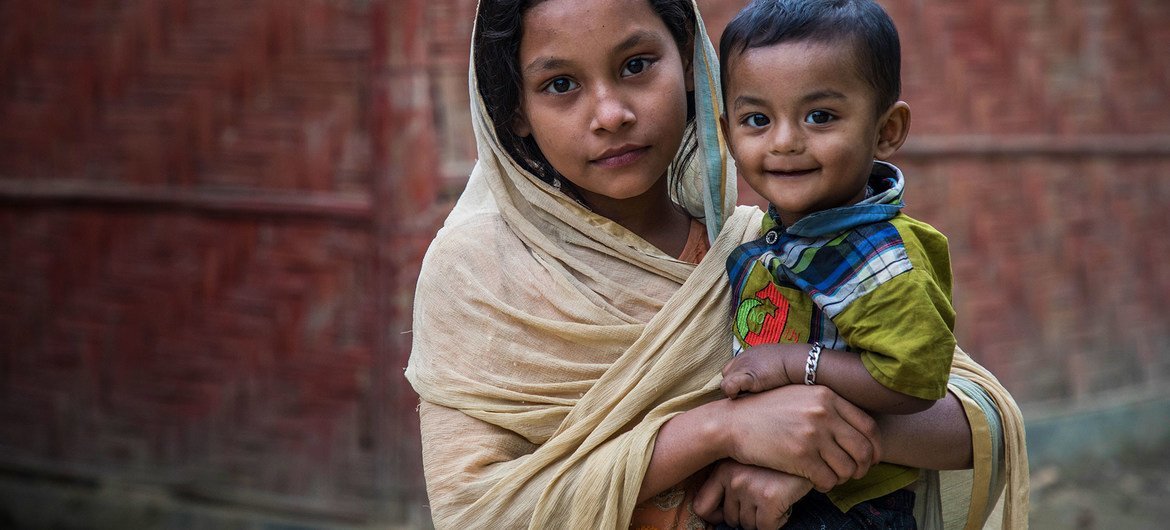 A young Rohingya girl holds her brother outside a youth club in Cox's Bazar, Bangladesh.