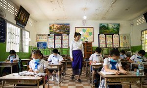 在柬埔寨的一所学校里，老师和学生戴着口罩，保持身体距离。
