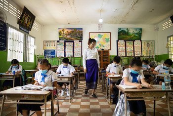 Une enseignante et des élèves portent des masques faciaux et maintiennent une distance physique dans une école au Cambodge.