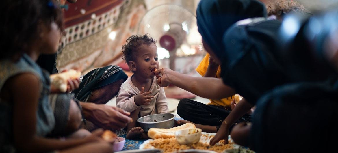 طفل عمره سنة يتناول الطعام مع أسرته في مخيم للنازحين داخليا في عدن، اليمن.