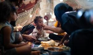 Un garçon âgé d'un an mange avec sa famille dans un camp de déplacés à Aden, au Yémen.