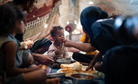 A one-year-old boy eats with his family in a displaced persons camp in Aden, Yemen.