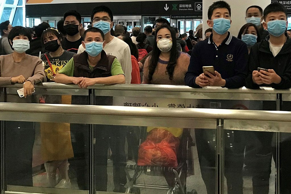 Des personnes portant un masque alors qu'ils attendent dans le hall des arrivées à l'aéroport international de Shenzhen, en Chine.