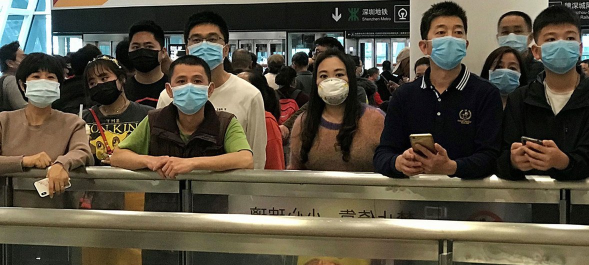 أناس يرتدون أقنعة صحية واقية بينما ينتظرون عند مطة وصول في مطار شنتشن باوآن الدولي في الصين.
