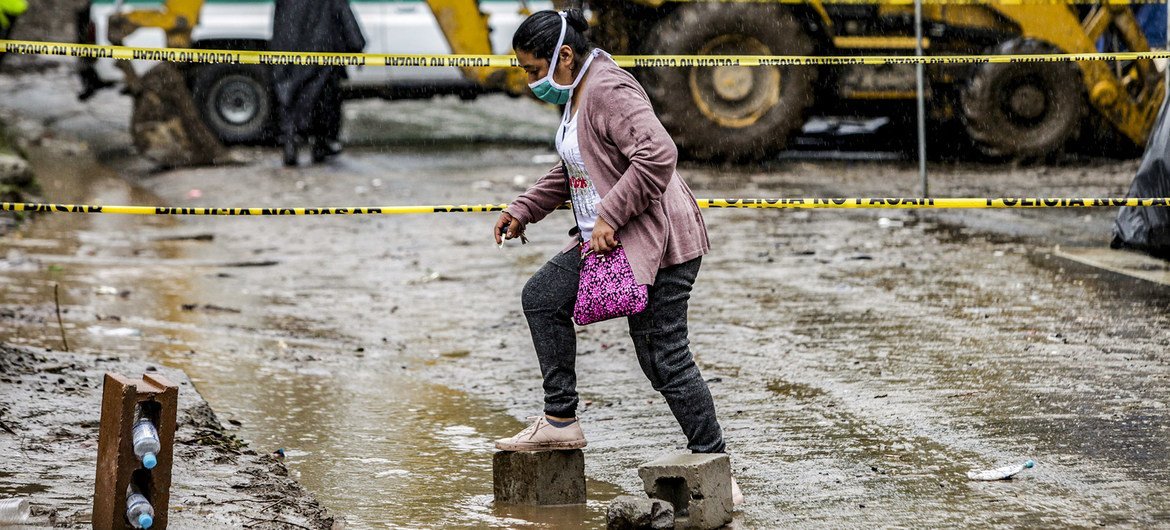 En kvinne går over en oversvømmet vei i Santo Tomás, San Salvador, etter at tropisk storm Amanda forårsaket et skred.