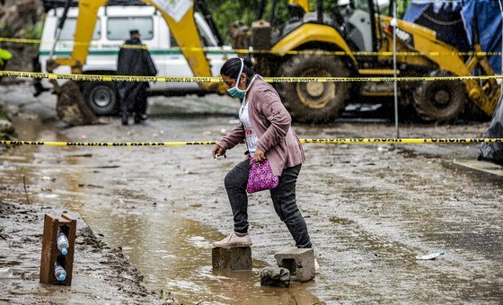 A woman walks across a flooded road in Santo Tomás, San Salvador, after Tropical Storm Amanda caused a landslide.