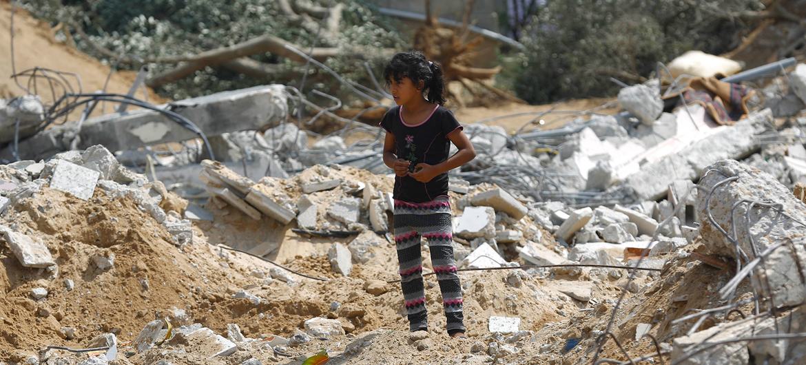 ग़ाज़ा पट्टी में इसराली बमबारी में ध्वस्त हुए एक तीन-मंज़िला मकान के बाहर एक लड़की.
