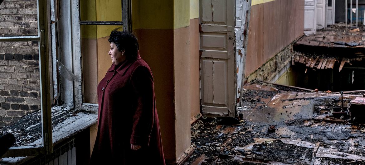 Mwanamke amesimama katika shule iliyoharibiwa na bomu huko Krasnohorivka, Oblast ya Donetsk, Ukraine.