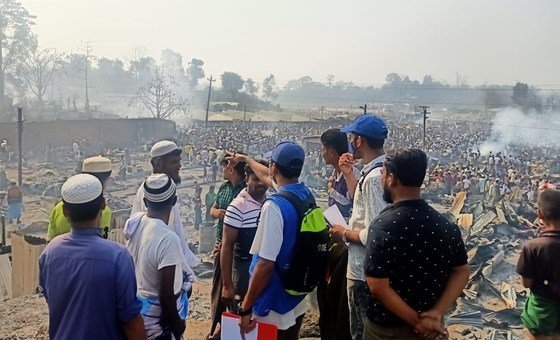 IOM personnel at Kutupalong refugee camp in Bangladesh. In the background are the tens of thousands of refugees displaced after the fire.