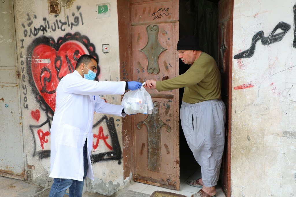 An UNRWA staff member provides medication to an elderly Palestine man in the Gaza strip.