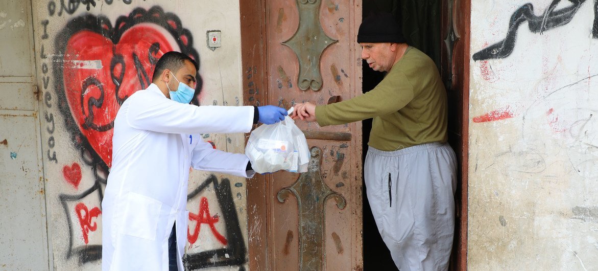 Un trabajador de UNRWA le ayuda con medicamentos a un anciano palestino en la Franja de Gaza.