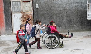 A disabled refugee girl from Syria in a wheelchair is helped by her sister as she and her other siblings head to school in Adana, Turkey.