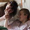柳德米拉亲吻她13岁女儿索菲亚的手，索菲亚在基辅奥克马蒂特儿童医院的一次炮弹袭击中幸存下来。