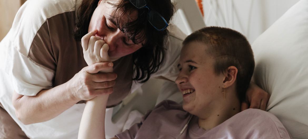 Lyudmila embrasse la main de sa fille Sofia, âgée de 13 ans, qui récupère d'une attaque au mortier dans un hôpital à Kyïv, en Ukraine.