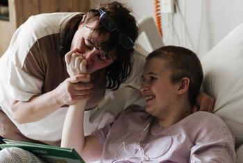 柳德米拉亲吻她13岁女儿索菲亚的手，索菲亚在基辅奥克马蒂特儿童医院的一次炮弹袭击中幸存下来。