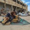 امرأة نازحة في إدلب السورية تجلس على الأرض في مدرسة مدمرة.