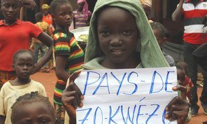 Menina da República Centro-Africana segura cartaz com o mote nacional, que significa que todas as pessoas são iguais