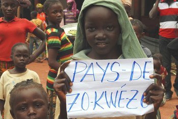 En République centrafricaine, une fillette tient un papier sur lequel est écrit Zo Kwe Zo, qui veut tous les êtres humains sont égaux.
