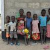 Kundi la watoto wanane limesimama nje ya jengo la shule ya matofali katika Kaunti ya Turkana, Kenya, wakiwa wamebeba vyombo vya maji na ndoo.