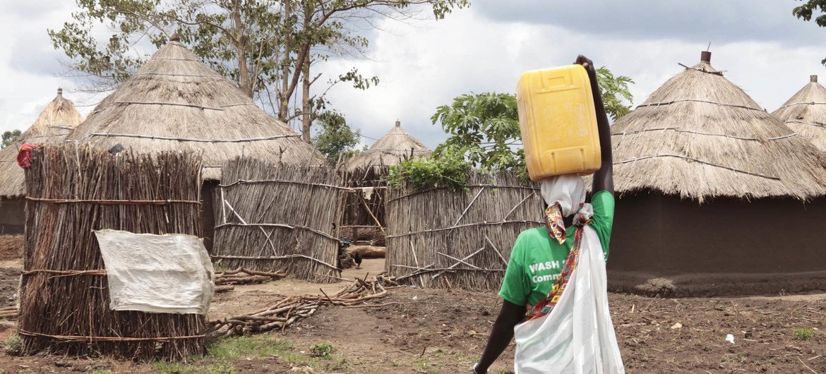 Uganda hosts the largest number of refugees in Africa. Pictured here, a South Sudanese refugee returns to her shelter after fetching water from a community tap at a refugee settlement in Adjumani district. (file photo)