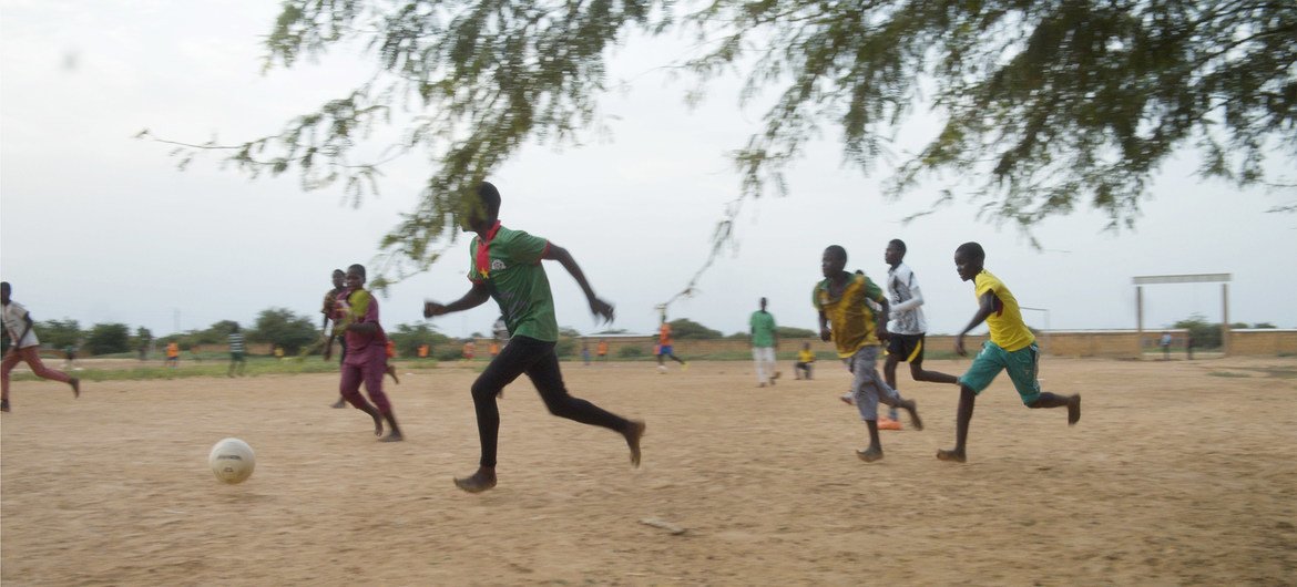 أطفال يلعبون كرة القدم في مساحة صديقة للأطفال تدعمها اليونيسف في بوركينا فاسو.