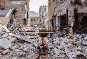 شاب يمني يجلس على ركام منازل دمرتها الحرب.