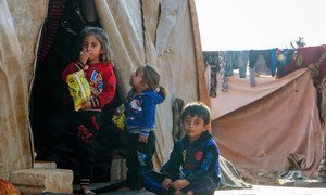 أطفال يحتمون من البرد مع أسرهم في مخيم غير رسمي في سوريا، قرب الحدود مع تركيا.