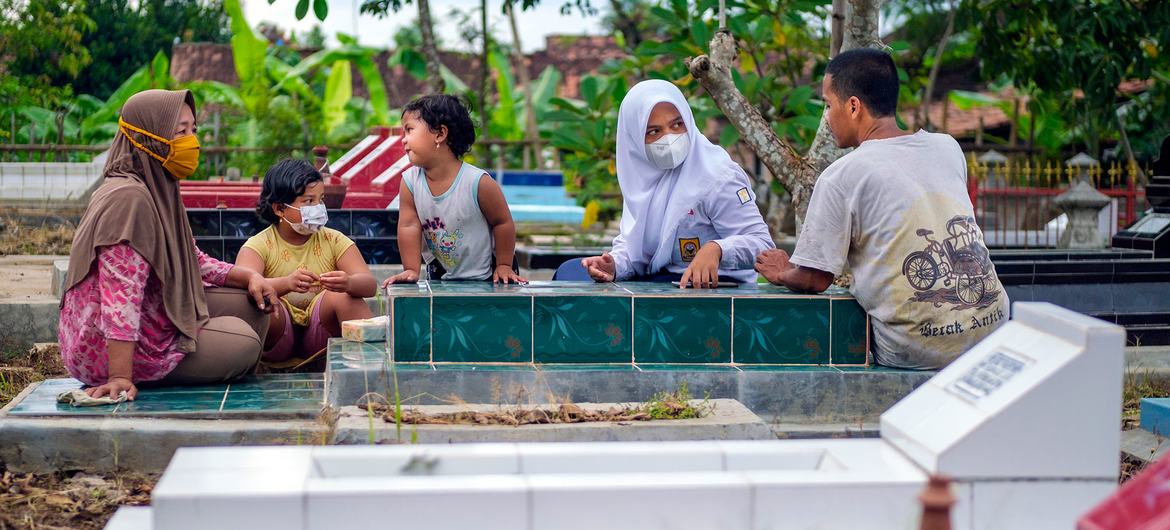 इण्डोनेशिया का एक परिवार, अपने एक परिजन की क़ब्र पर, जिसकी मृत्यु कोविड-19 के संक्रमण से हुई.