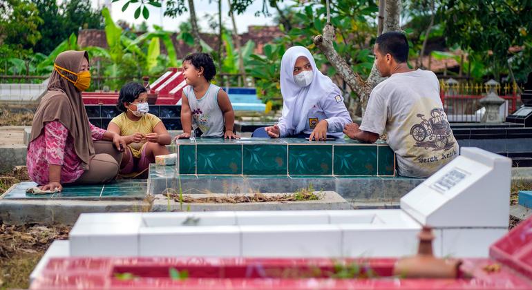 A family visit the grave of their mother who worked at a popular restaurant in Indonesia where she likely contracted COVID-19. 