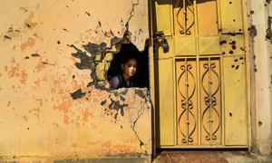 A young girl looks through a hole in the wall from damage from conflict in a school in Ramadi, Anbar Governorate, Iraq. (file)