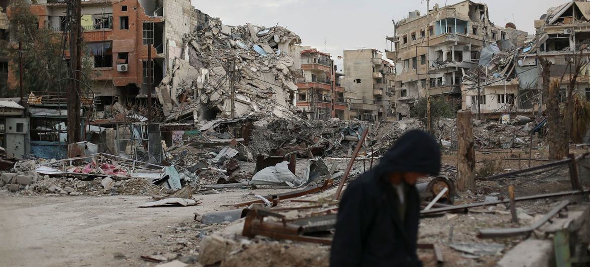 Un homme marche devant des bâtiments détruits à Harasta, en Syrie.