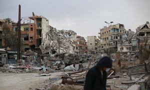 A man walks in front of destroyed buildings in Harasta, Syria.