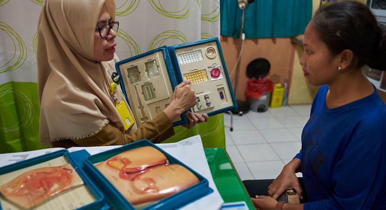 Uma conselheira mostra a uma mulher opções de controle de natalidade no centro de saúde na Indonésia.