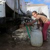 叙利亚西北部的一个境内流离失所者营地里，一名年轻女孩从一辆油罐车上取水。