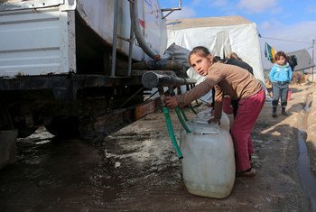 A young girl collects water from a tanker truck in an IDP camp in northwest Syria.