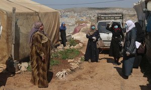 Standing on the left, a volunteer working to raise awareness on COVID-19 at an IDP camp in northern Idlib, Syria. Displaced from Homs herself, she knows the importance of helping protect the IDPs.