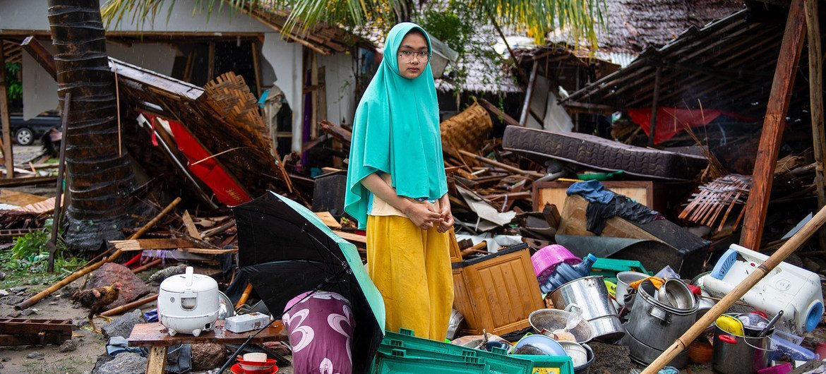 An girl stands outside her home which collapsed when a tsunami struck Java and Sumatra, Indonesia’s two most populous islands.