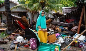 An girl stands outside her home which collapsed when a tsunami struck Java and Sumatra, Indonesia’s two most populous islands.
