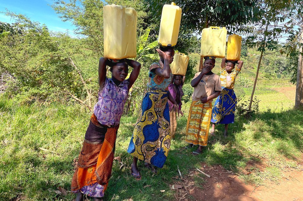 Unas jóvenes cargan pesadas garrafas de agua a sus hombre de una fuente en Ituri, en la República Democrática del Congo.