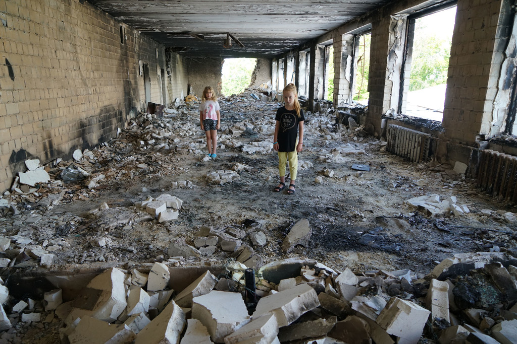 在乌克兰布佐瓦，两位8岁的儿童站在她们受损学校的瓦砾中。