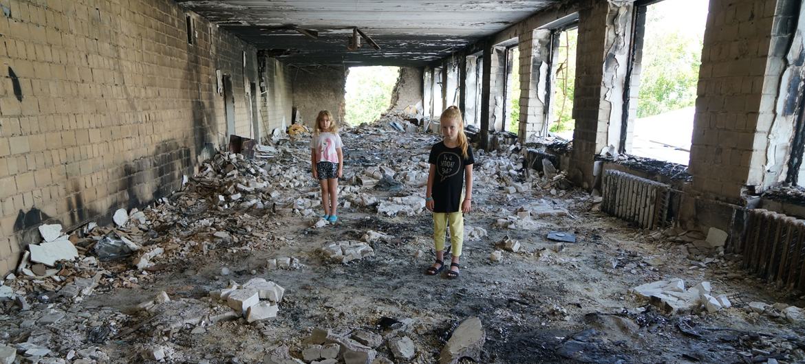 Unas amigas de ocho años en medio de los escombros de su escuela dañada en Buzova, Ucrania.