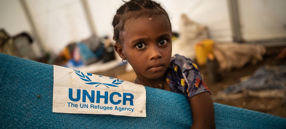 सूडान के हमदायेत में एक अस्थाई शिविर में बिस्तर वग़ैरा ले जाती एक इथियोपियाई शरणार्थी बच्ची.