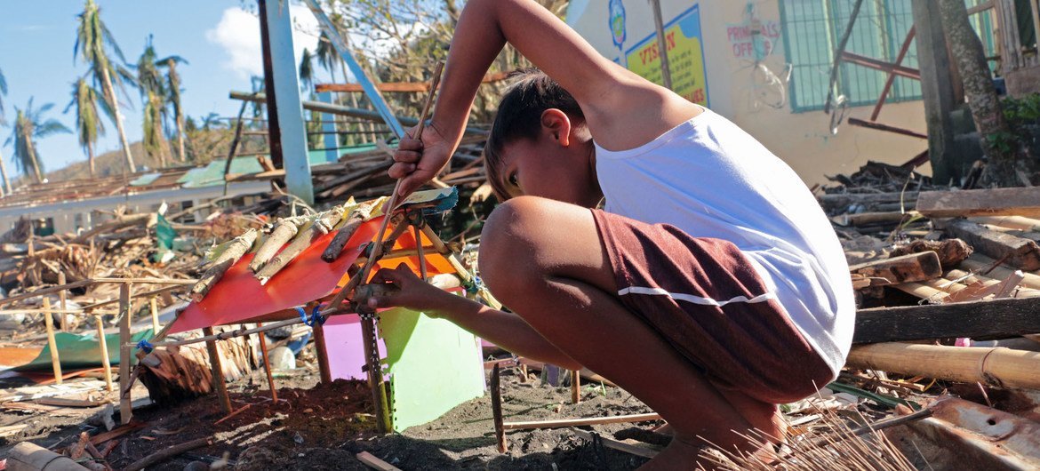 A boy makes a small house using plastic and debris. His home was completely swept away when Typhoon Goni hit the Philippines in November 2020.