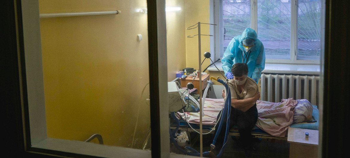 यूक्रेन में एक डॉक्टर कोविड-19 मरीज़ की स्वास्थ्य जाँच कर रहा है.