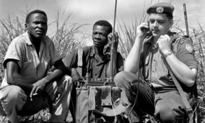 Le Casque bleu canadien Signalman J.T. Shier, avec deux ouvriers congolais, est de service à l'entrée d'un champ de tir où les soldats congolais sont formés au tir de précision.