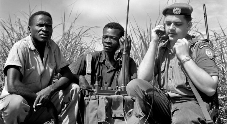 Le Casque bleu canadien Signalman J.T. Shier, avec deux ouvriers congolais, est de service à l'entrée d'un champ de tir où les soldats congolais sont formés au tir de précision.