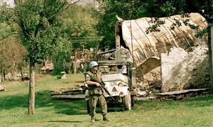 Un Casque bleu canadien servant dans la Force de protection des Nations Unies (FORPRONU) monte la garde près d'une maison détruite en Croatie.