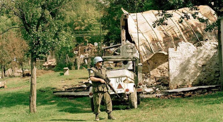 A Canadian peacekeeper serving with the UN Protection Force (UNPROFOR) stands guard near a destroyed house in Croatia.