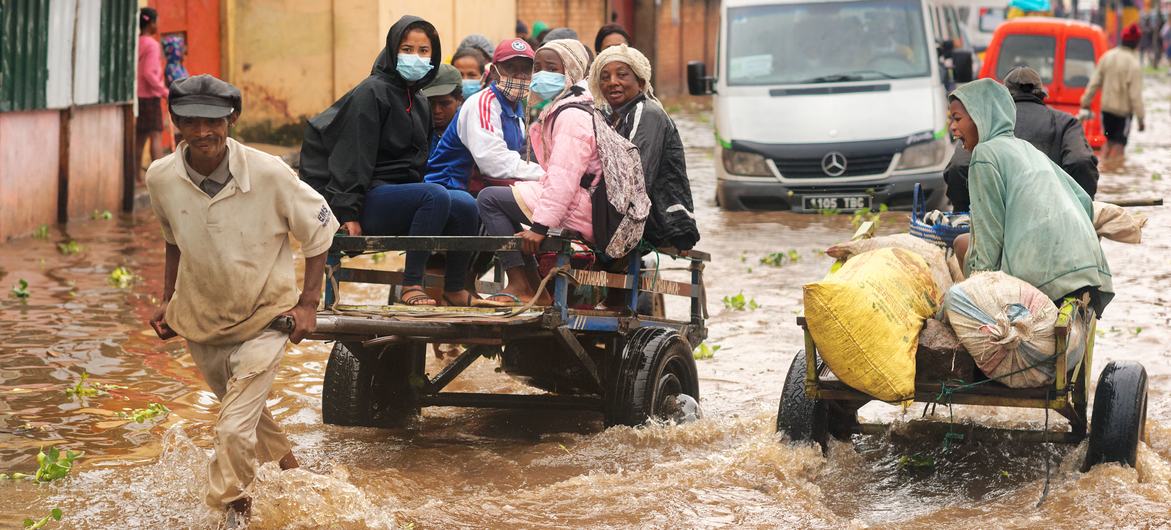 Un homme transporte des personnes sur un chariot alors que la route principale est inondée dans le district d'Ilanivato, Antananarivo. Madagascar.